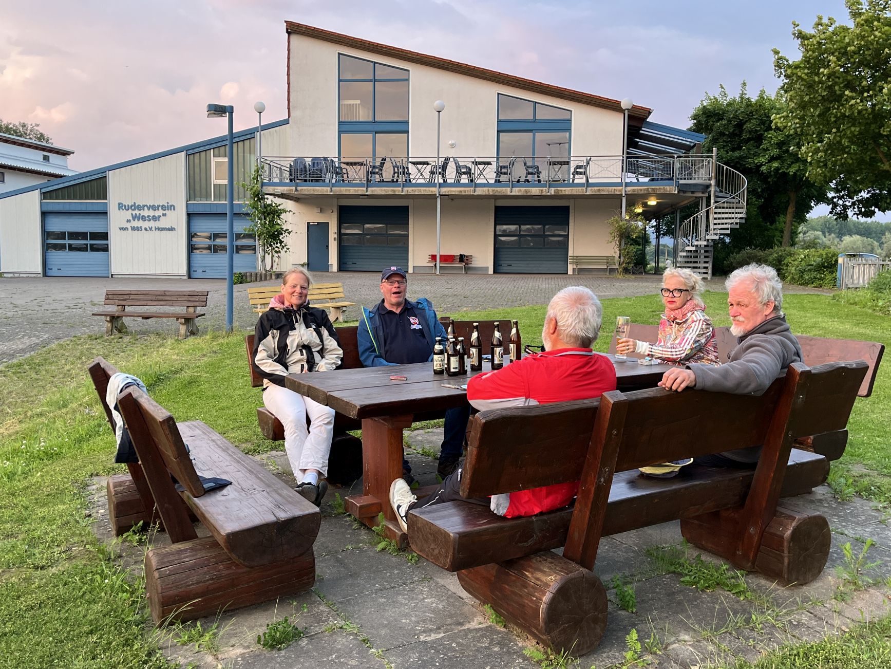 5 Menschen sitzen an einem Tisch vor der Bootshaus des Rudervereins "Weser"
