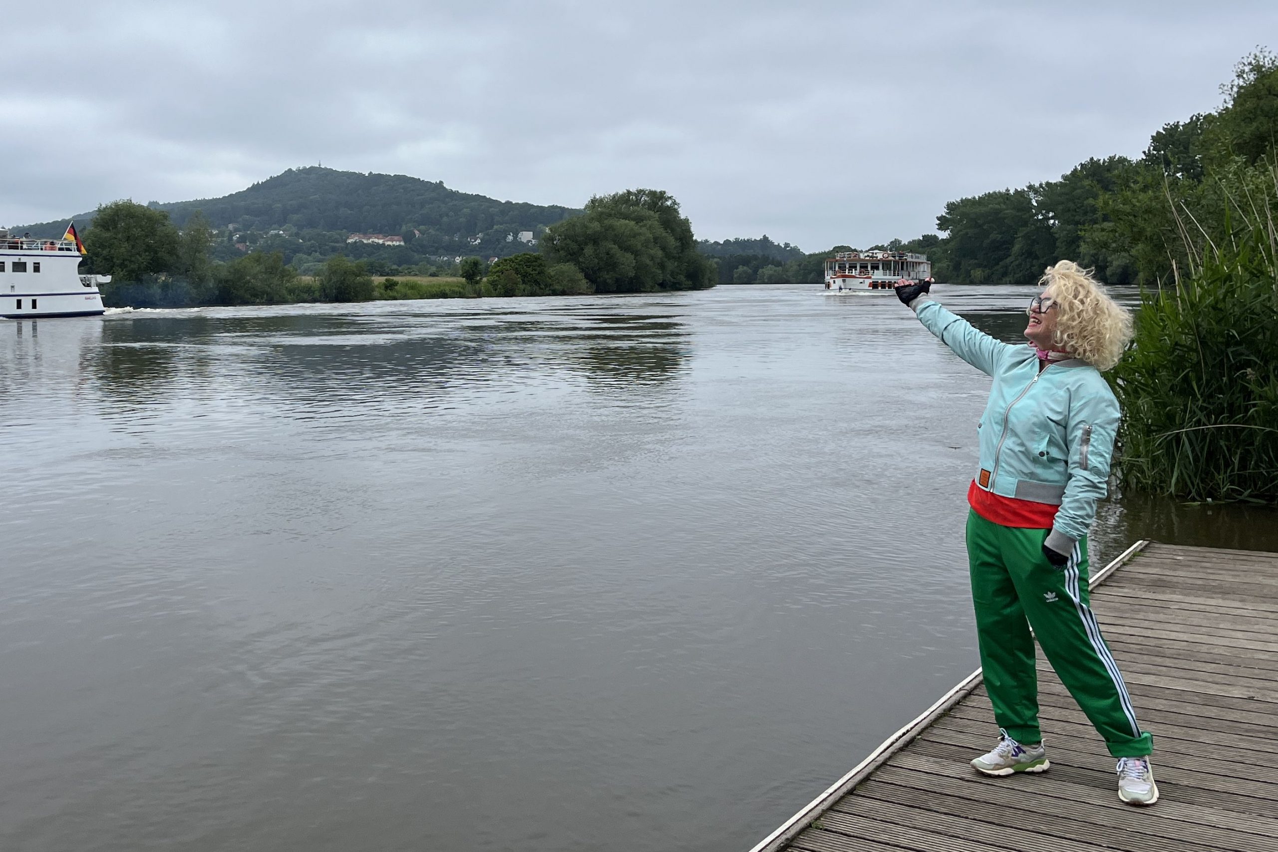 Zwei Schiffe auf der Weser, davor steht eine Person auf dem Steg und zeigt auf das hintere Schiff