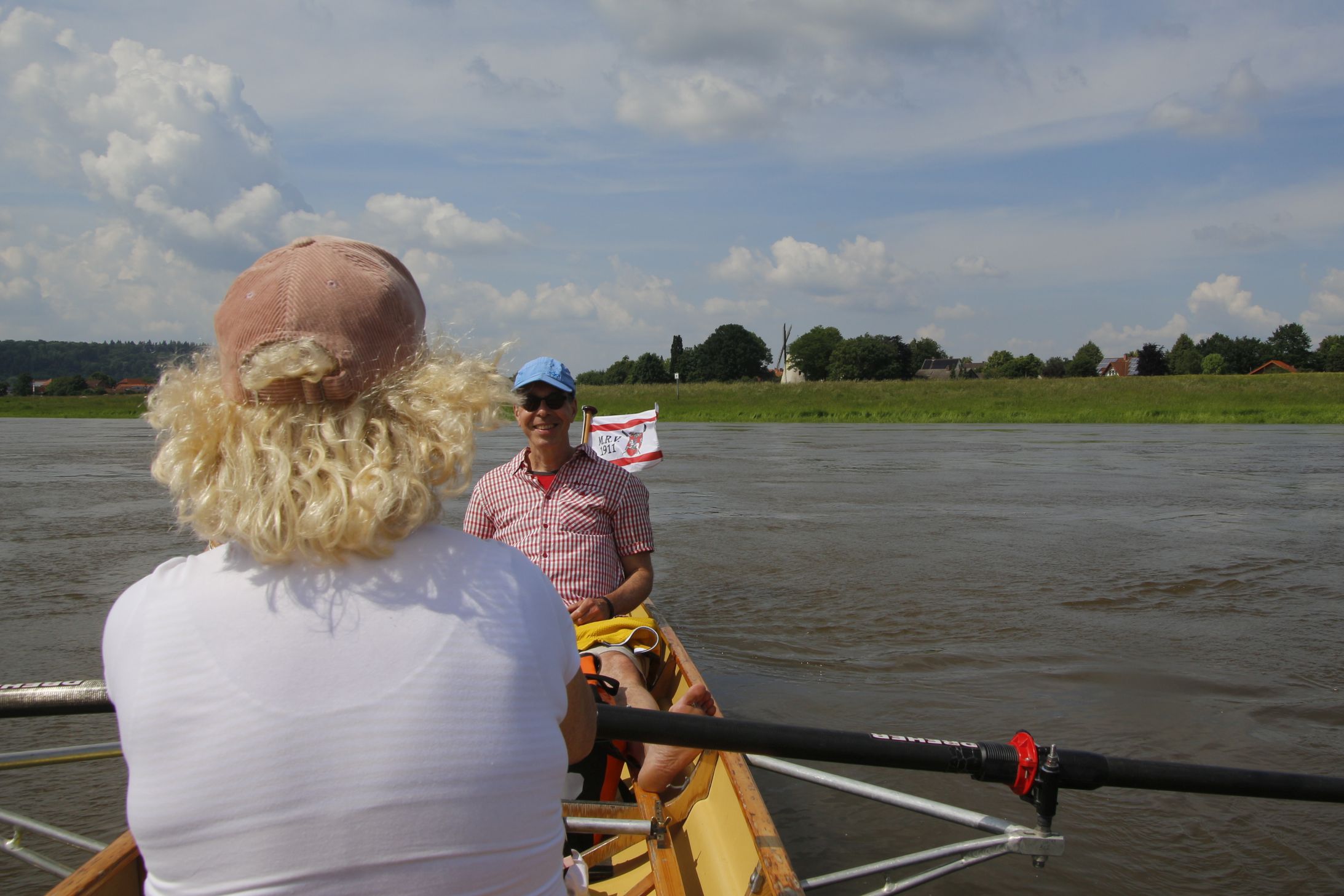Zwei Menschen in einem Ruderboot, im Hintergrund ist eine Mühle zu sehen